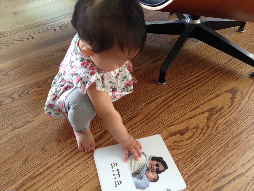 Toddler looks at her grandma's photo in her board book.
