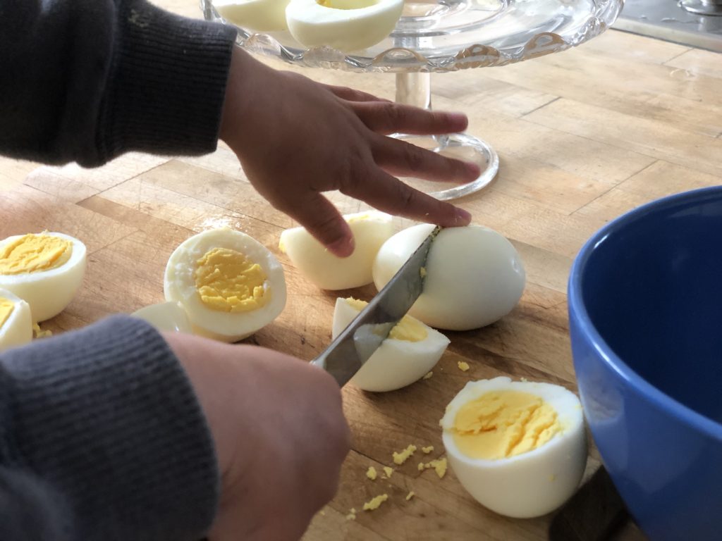A small child will halved the eggs crosswise. Remove the yolks, mash with mayonnaise, season with salt, and pipe the yolks back into the egg whites.