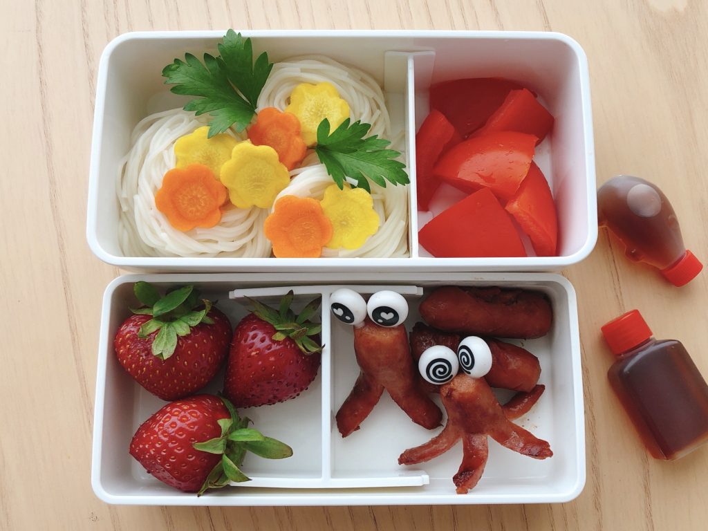 Cold somen noodles with dipping sauce, tomato wedges, strawberries and little sausages turned into octopuses make up this bento box.

