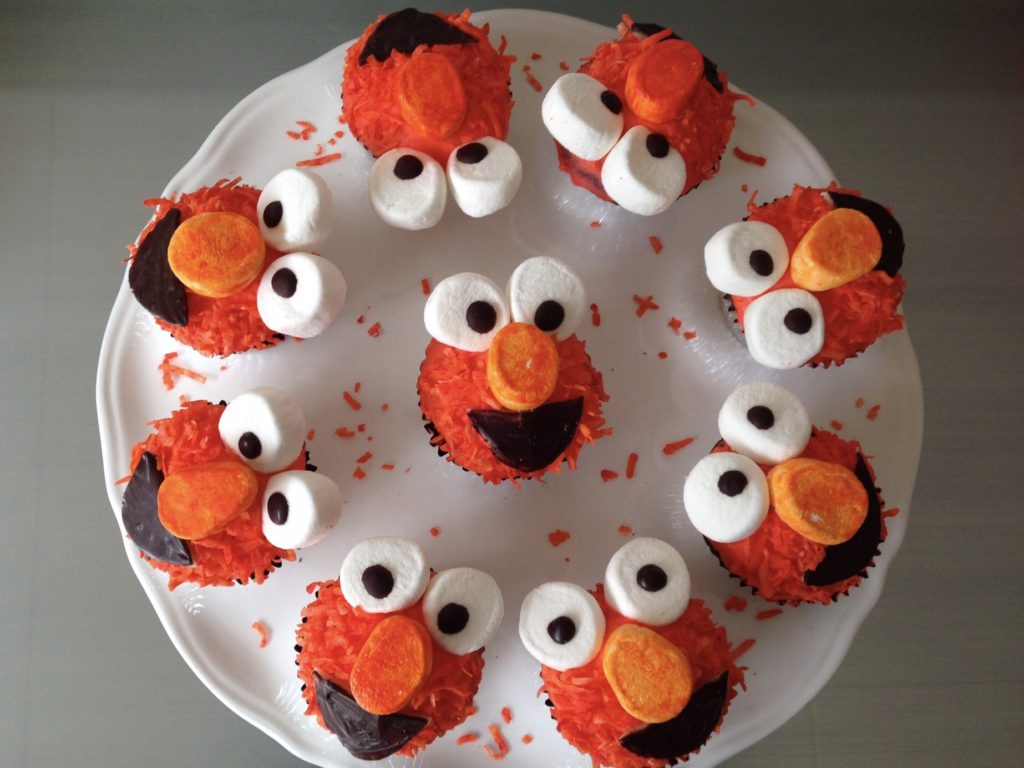 Finished Elmo cupcakes are arranged on a cake plate, ready for serving.
