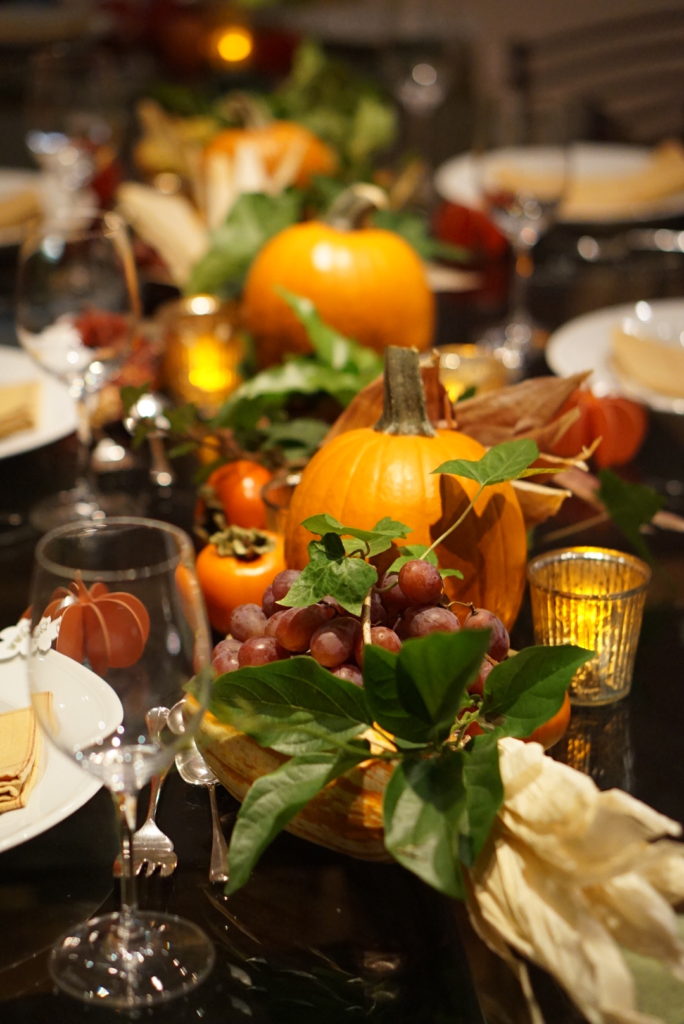 Pumpkins, persimmons, pomegranates and sheaves of Indian corn are grouped on the table, with bunches of grapes and handfuls of ivy.  The tea lights are battery-operated.