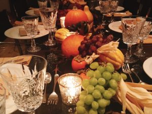 Thanksgiving table features pumpkins, grapes, and other fall produce.
