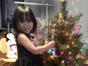Miss T decorates the child's Christmas tree in the playroom.