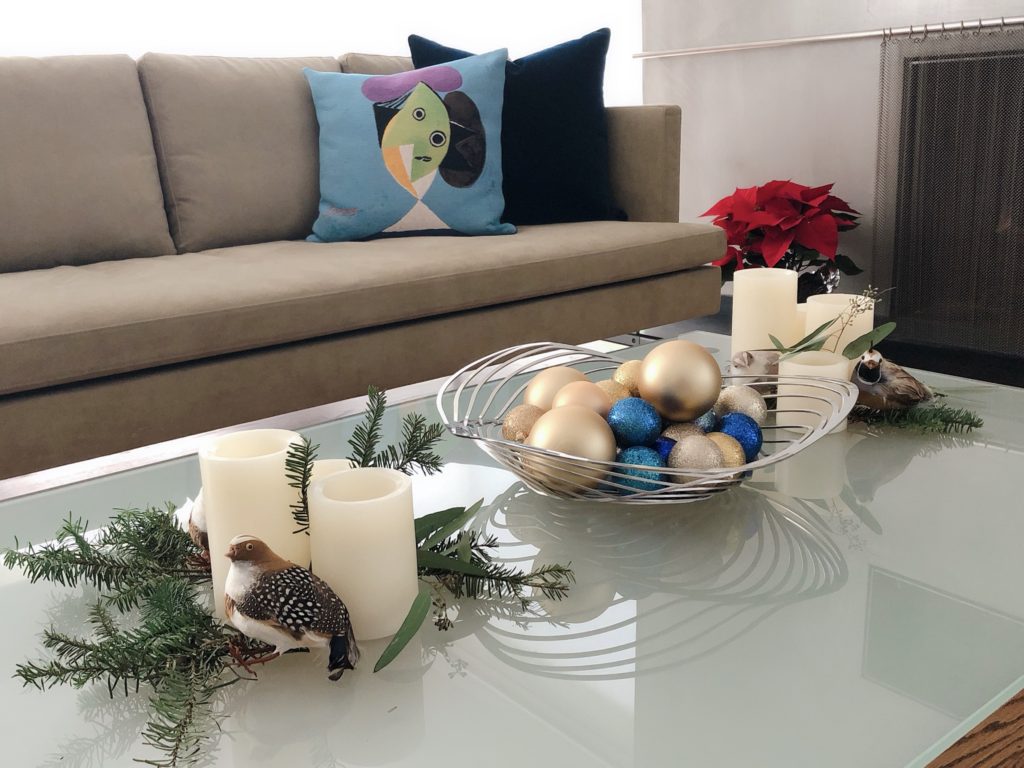 Discarded Christmas tree branches, battery-operated pillar candles, partridges, and Christmas balls decorate this coffee table.
