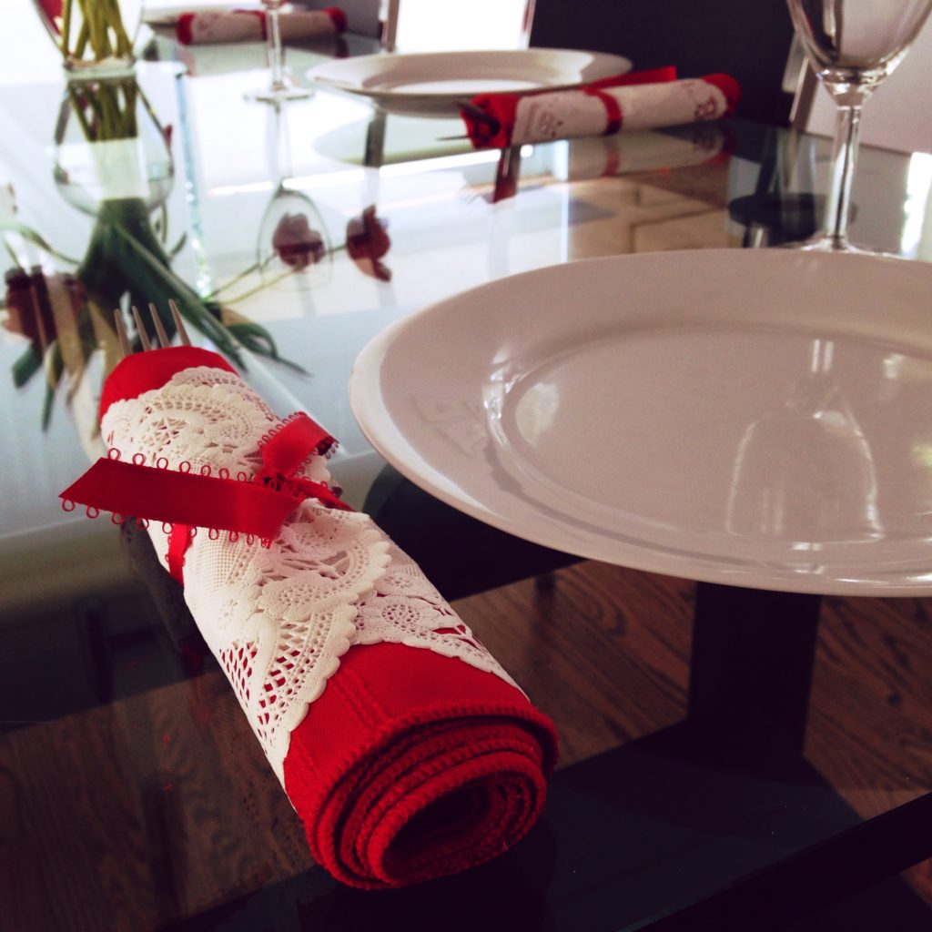 A simple napkin treatment, wrapping a red napkin in a paper doily and tying with ribbon is perfect for a Valentine's Day dinner.