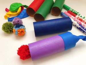 To make pompom canons, you need balloons, pompoms, and toilet paper rolls.