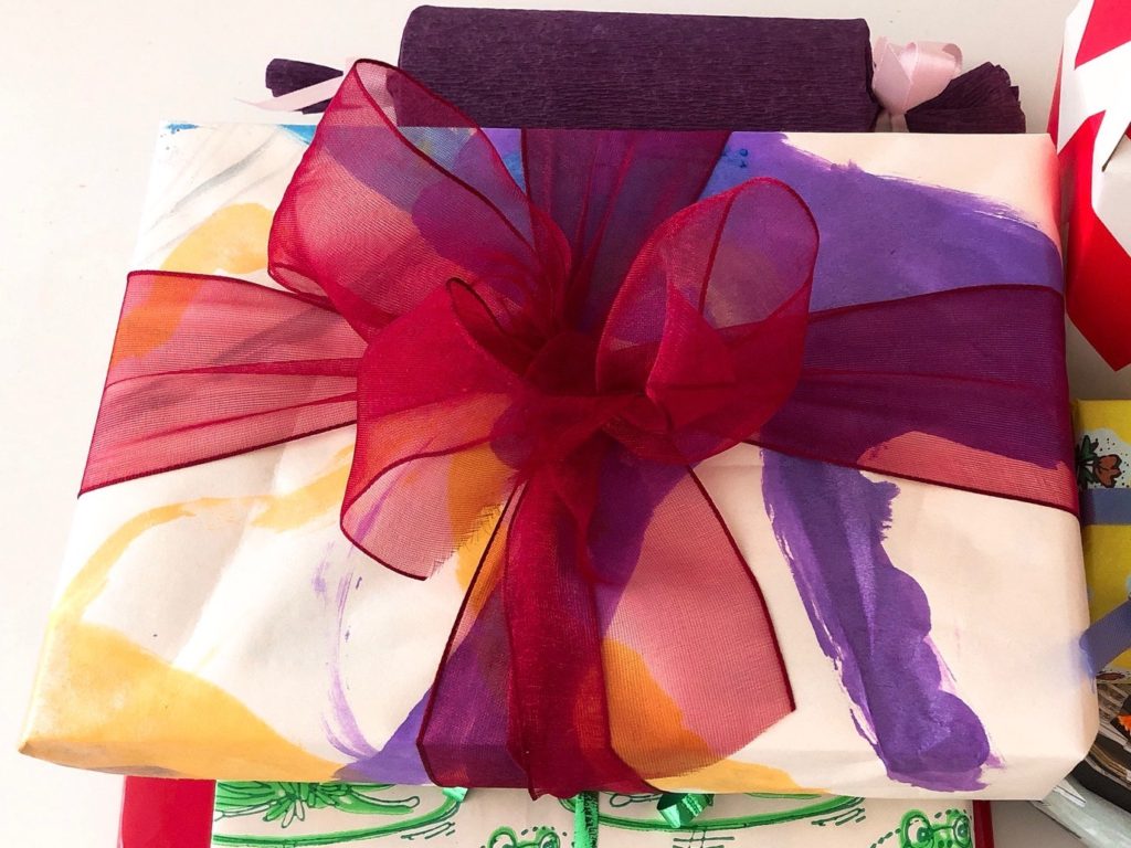 Wrap a present in gift wrap made by recycling children's paintings.