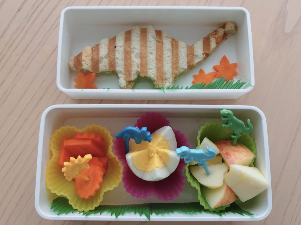 Dinosaur panini sandwich, carrots an egg flower and apple chunks make up this dinosaur bento lunch box.