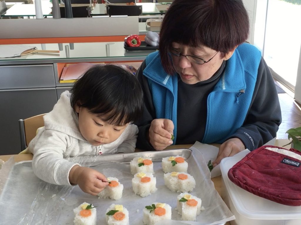 Making sushi at home. Grandma and her three-year-old grandchild make sushi together.
