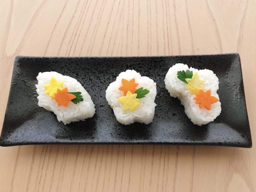 This sushi, made at home, is shaped with a mold and decorated with egg and carrot leaves and a bit of parsley.
