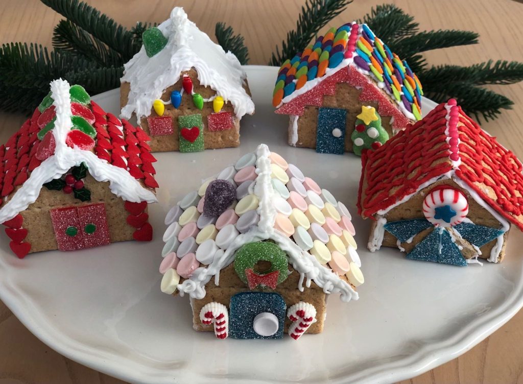 Candy, white tube icing, and cookie decorating sprinkles are used to make these houses constructed with graham cracker squares.