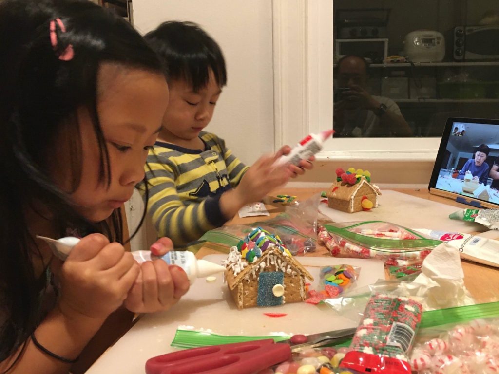 Children making gingerbread houses as a remote, FaceTime activity with grandparents.