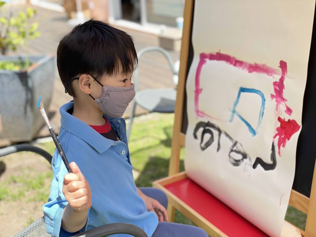 Painting outdoors is a fun activity for the grandkids. This child, working at an easel, is painting a fire truck.