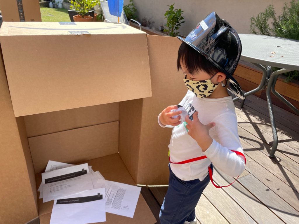 Secure in hist box fort, a child makes paper balls as ammunition to repel the "enemy."