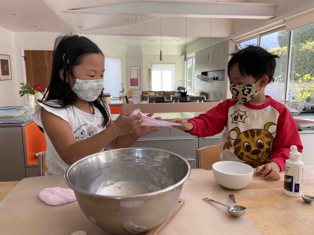 Children, having made slime, pull and stretch it to begin play.