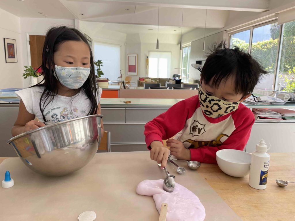 Child sticking a measuring spoon into slime. Making slime is a good project when you're wondering what to do with the kids.