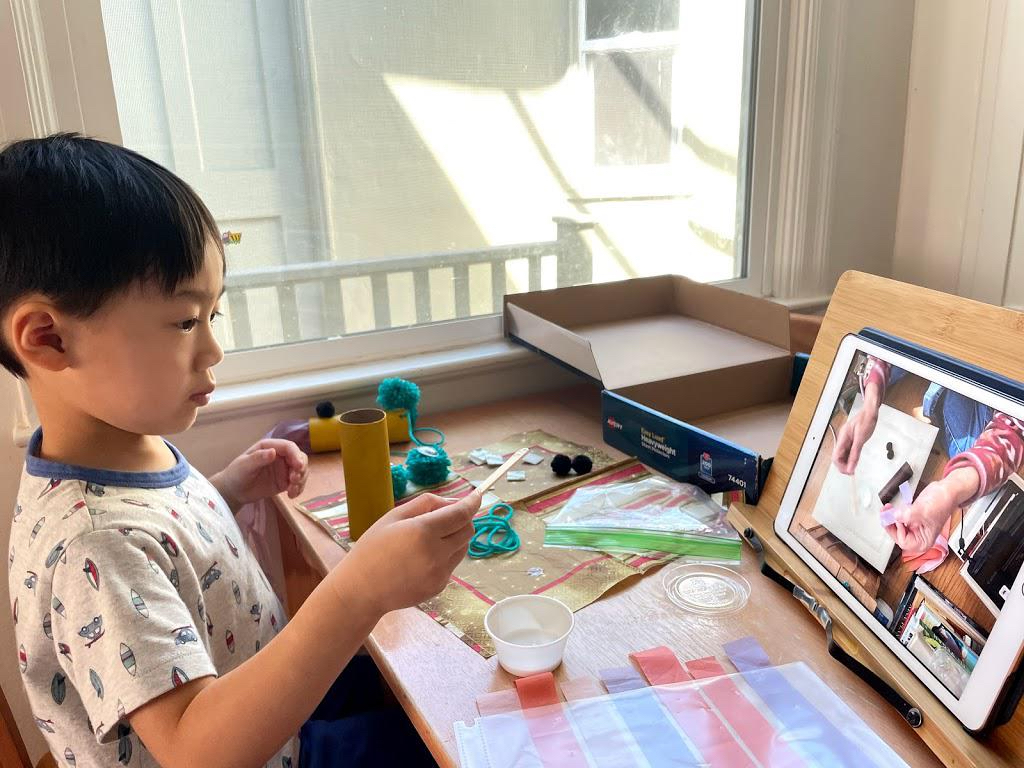 Preschooler makes a craft project watching grandma's demo on FaceTime. It's a way to stay connected with grandkids when apart.