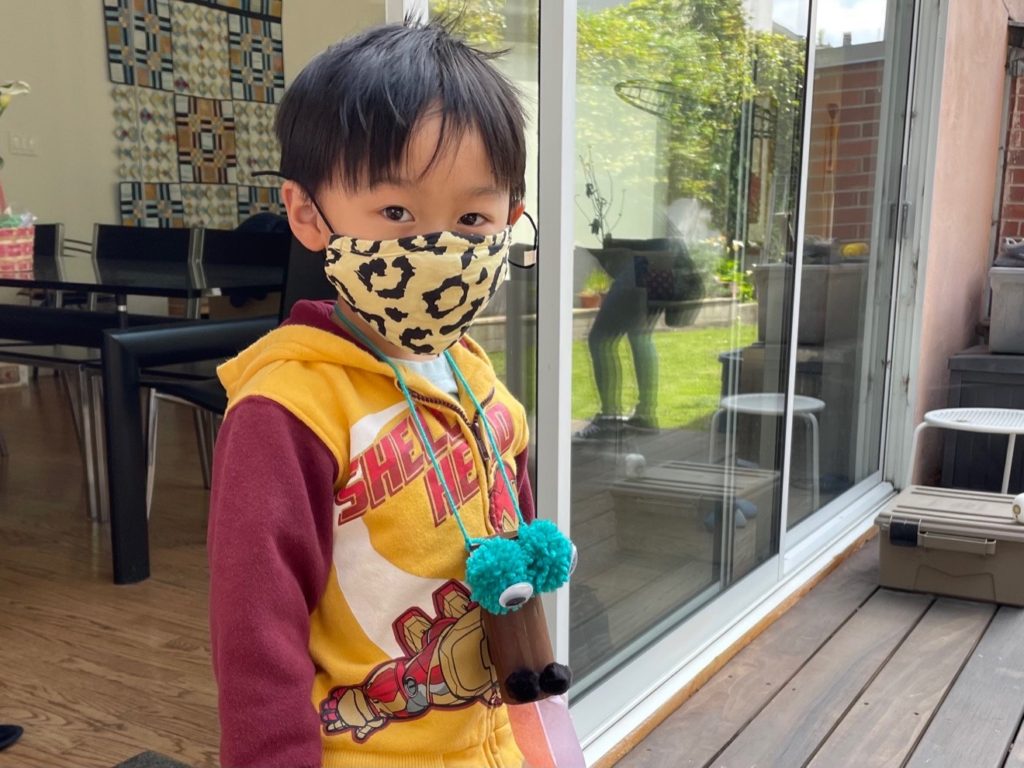 Child wearing a fire-breathing dragon that he made with toilet paper rolls and tissue paper.