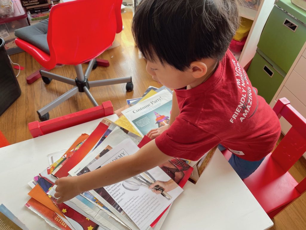 Child reviews magazine pages to select images to create a story.