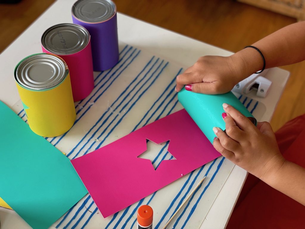 Cover the can with solid cardstock and secure with glue gun. Re-cover with contrasting cardstock with cut-out star and glue in place.