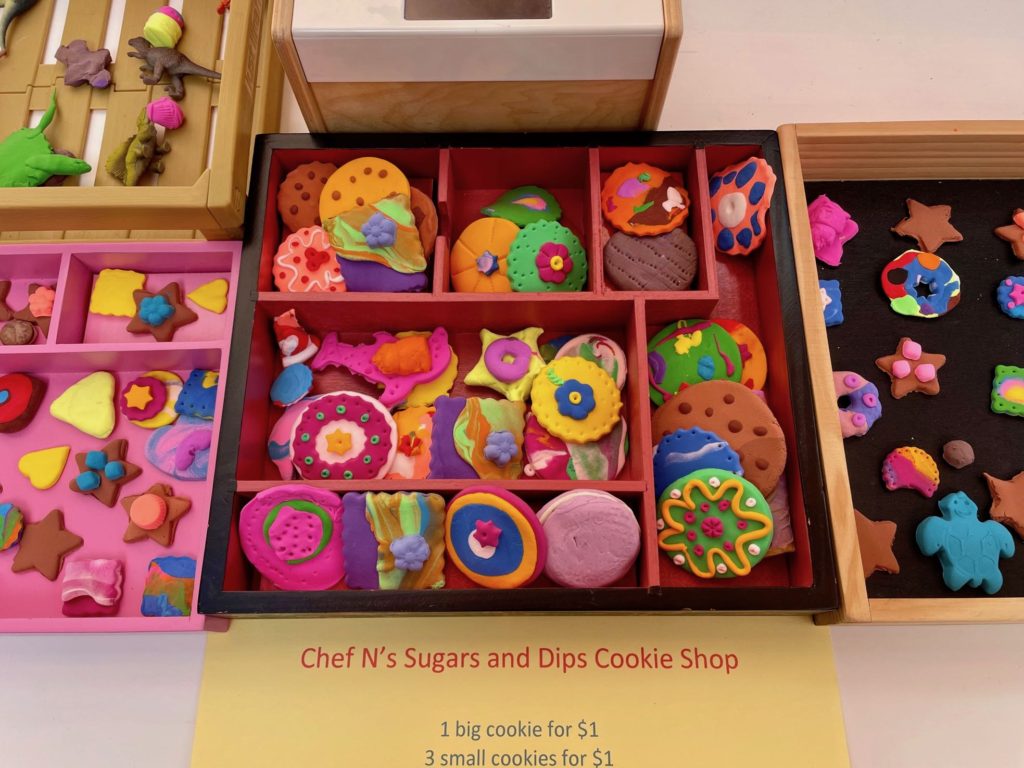 A variety of colorful, air-dried clay cookies are set up for sale at the cookie shop.