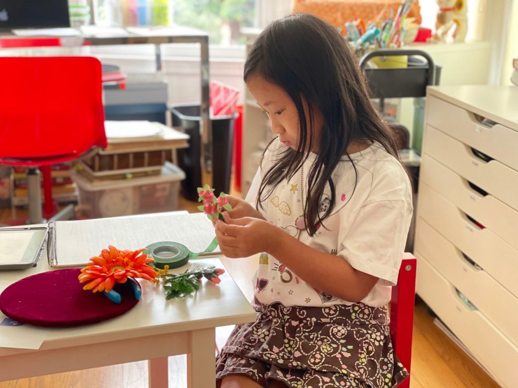 Decorating the fascinator with flowers .