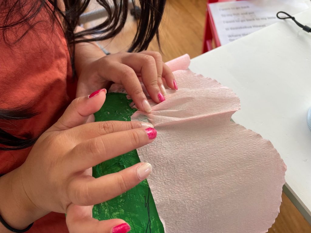 To make a flower piñata, attach petals, by gluing on crepe paper an inch or so at a time, using your fingers to scrunch the paper and create gathers.