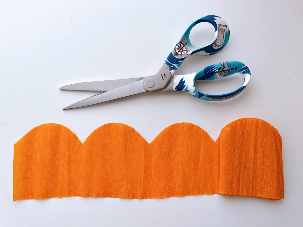 To make flower petals for the piñata, fold crepe paper and cut the top in scallop shape.