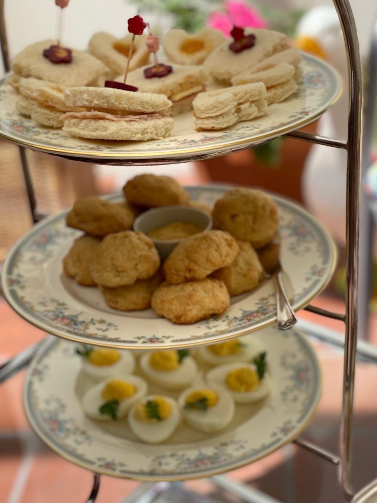 Three-tiered rack holds tea sandwiches, scones, and deviled eggs.