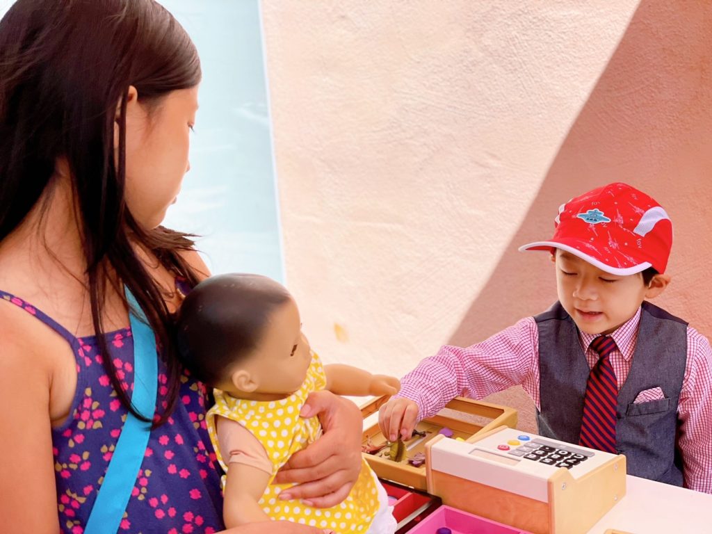 A child and her baby doll visits the pretend cookie shop.