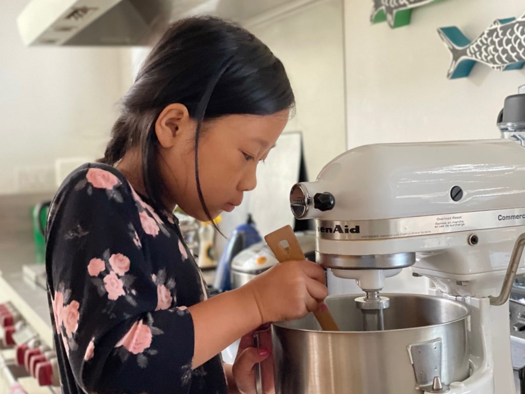 Child mixing up cookie dough for a Camp Grandma tea party.