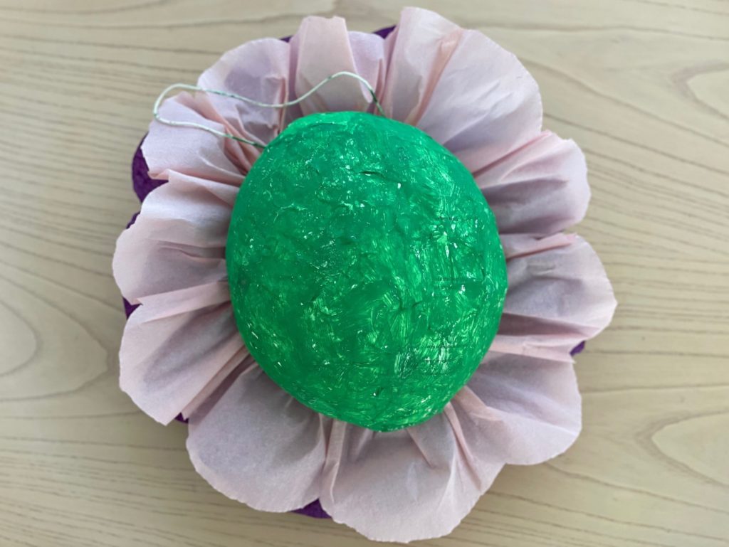 The back of the  piñata is green paint, while the front of the  piñata is decorated to look like a flower.