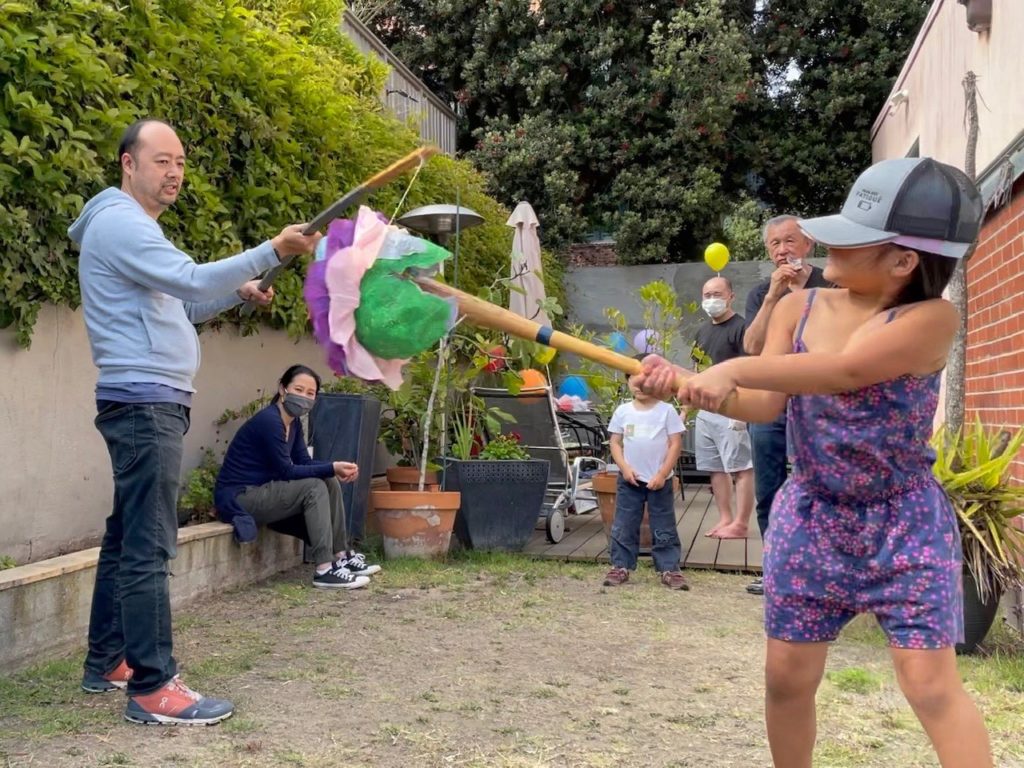 Child cracks open the  piñata with a heavy swing with the bat.