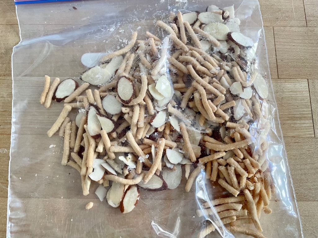 Crushed chow mein noodles and toasted slivered almonds are combined in a bag, ready to mix with melted white chocolate.