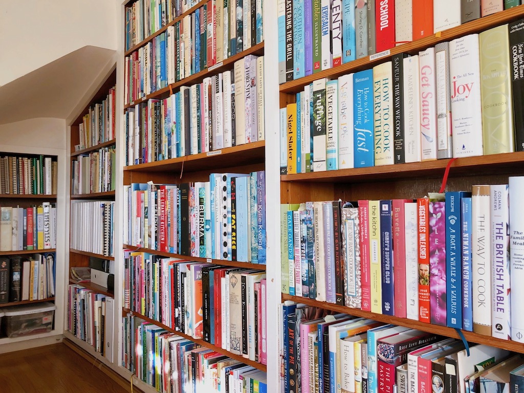 Cookbooks and craft books are stored on built-in shelves under a stairwell nook.
