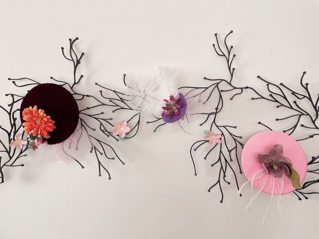 Fascinators made for a tea party during Camp Grandma are displayed on the wall.