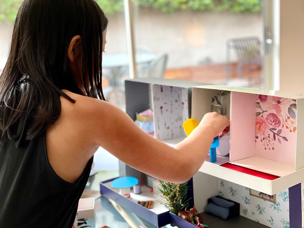 Child sets furniture into dollhouse.