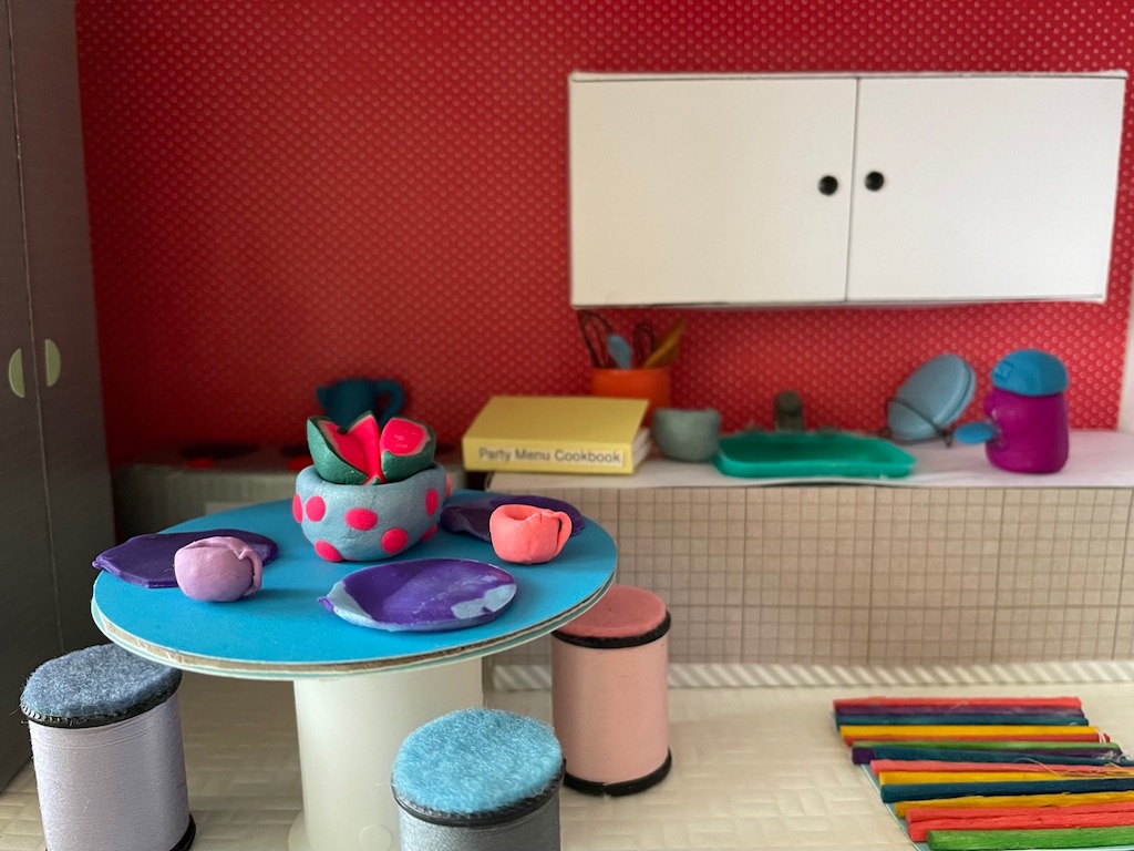 The kitchen is fitted with plates, cups, a tea kettle and Nespresso machine, all made by a child.