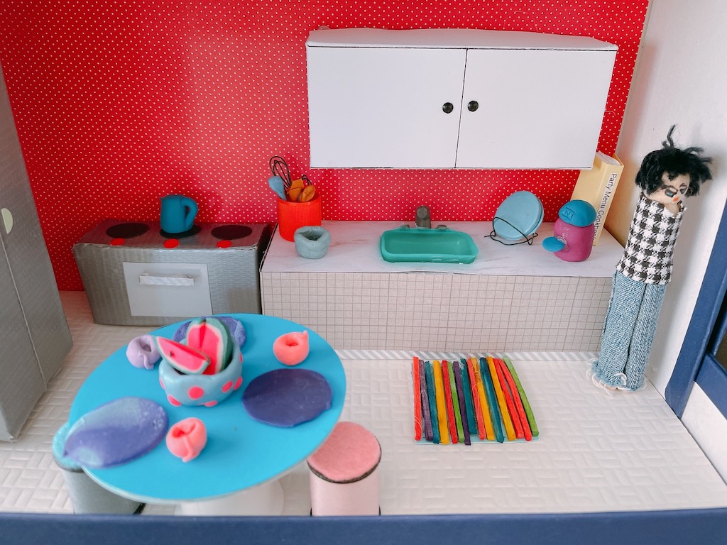 The DIY dollhouse kitchen features appliances made with boxes covered in duct tape and accessories made from polymer clay.