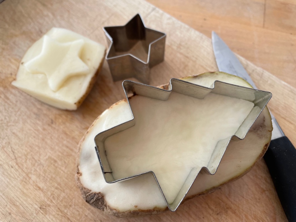 To make potato stamps for tags and wraps, halve potato, imbed cookie cutter, and cut around the edges of the potato so the image is raised.