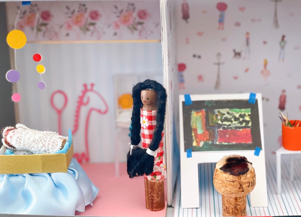 The nursery has a basinet made out of a box and ribbons and a mobile made from circle stickers on wire. The art studio has an easel made of cardboard, a champagne cork seat, and color pencils made from toothpicks set in a glue stick cap.