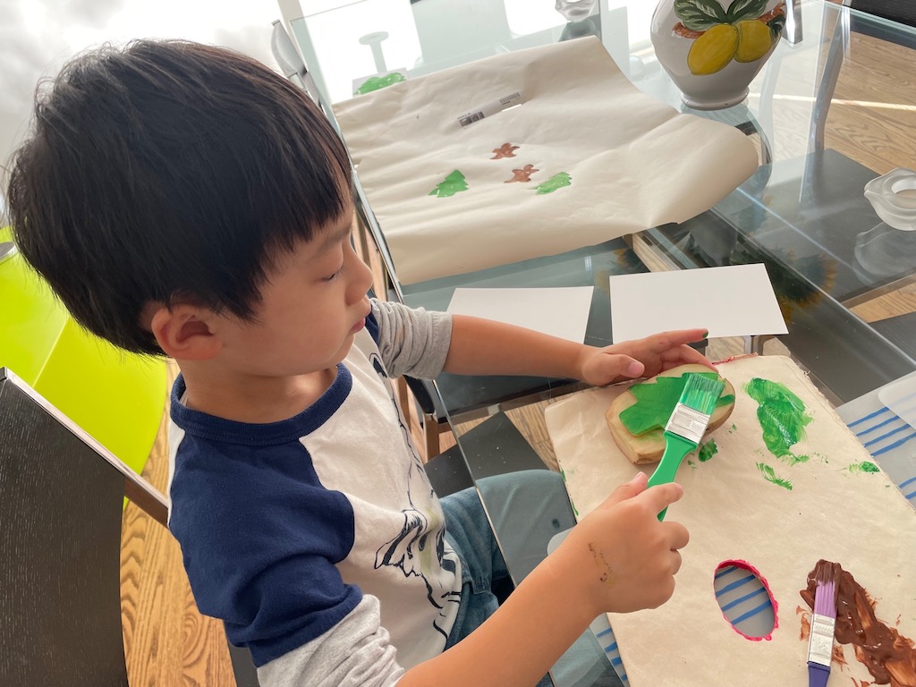 Child makes gift wrap using a potato stamp.