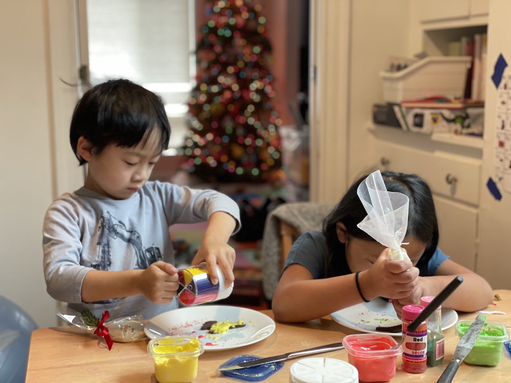 Kids are busy decorating Christmas cookies.