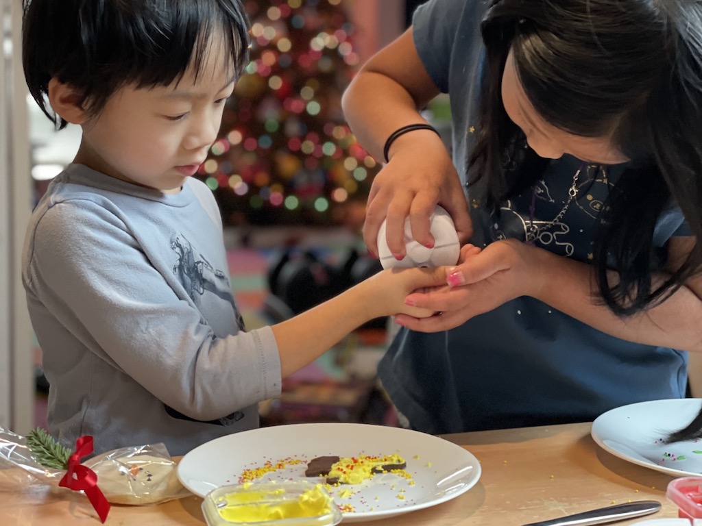 Big sister helps little brother with sprinkles to use in cookie decorating.