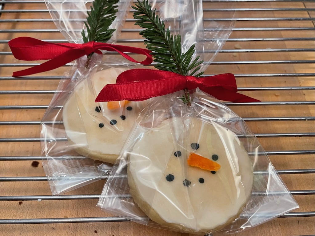These snowman cookies are made with slice-and-bake butter cookies, covered in white icing, with dots of black icing for the eyes and mouth. Orange gumdrop slivers make the nose.