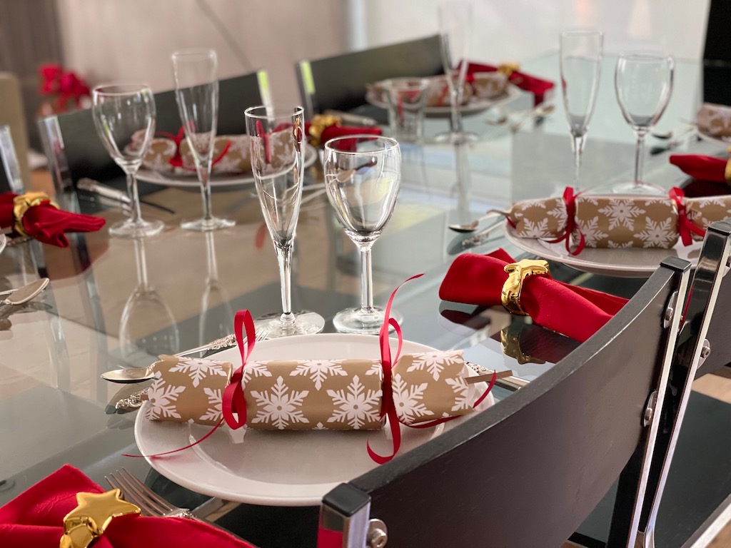 Introduce color to the neutral table accoutrements through Christmas crackers and red napkins. The table is beginning to reflect this special dinner with grandkids.
