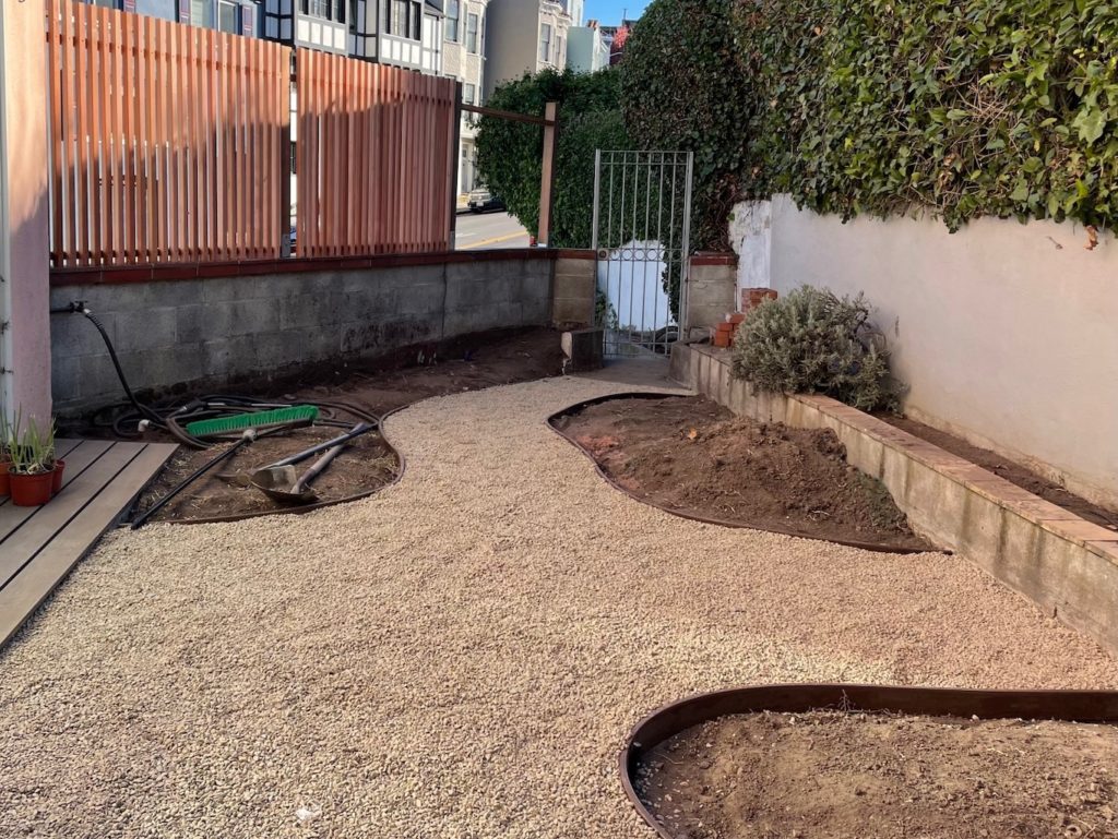 The redwood fence is almost complete; the pea gravel path is in place.