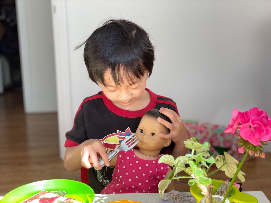 Child feeds a doll, learning to model parenting behavior in the best game to teach kids life lessons.