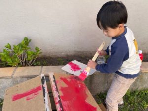 Child painting a cardboard box to use as a fort.