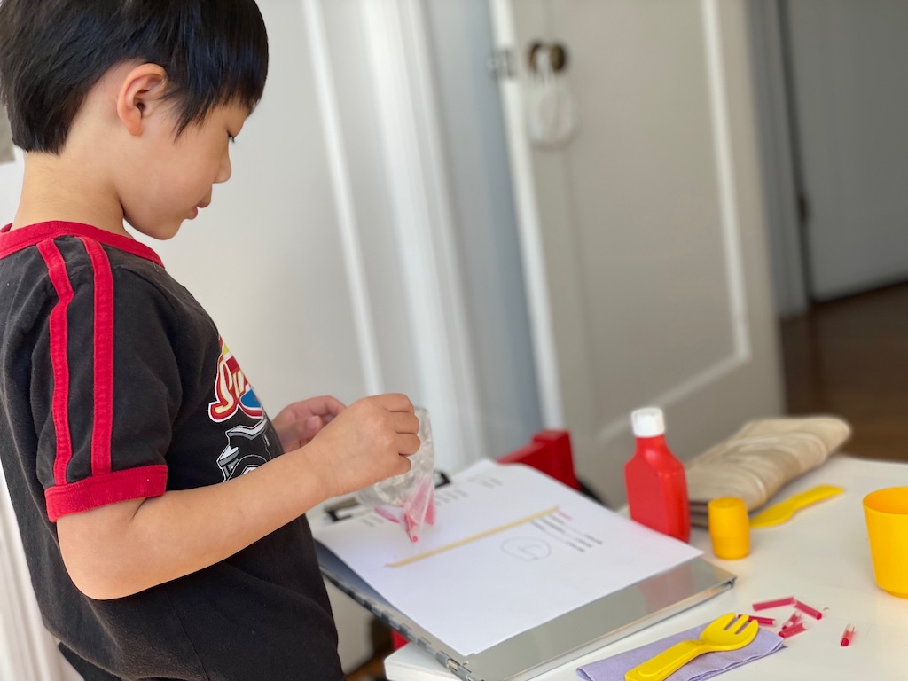 Child counts out drinking straw snippets. Each snippet represents $1.